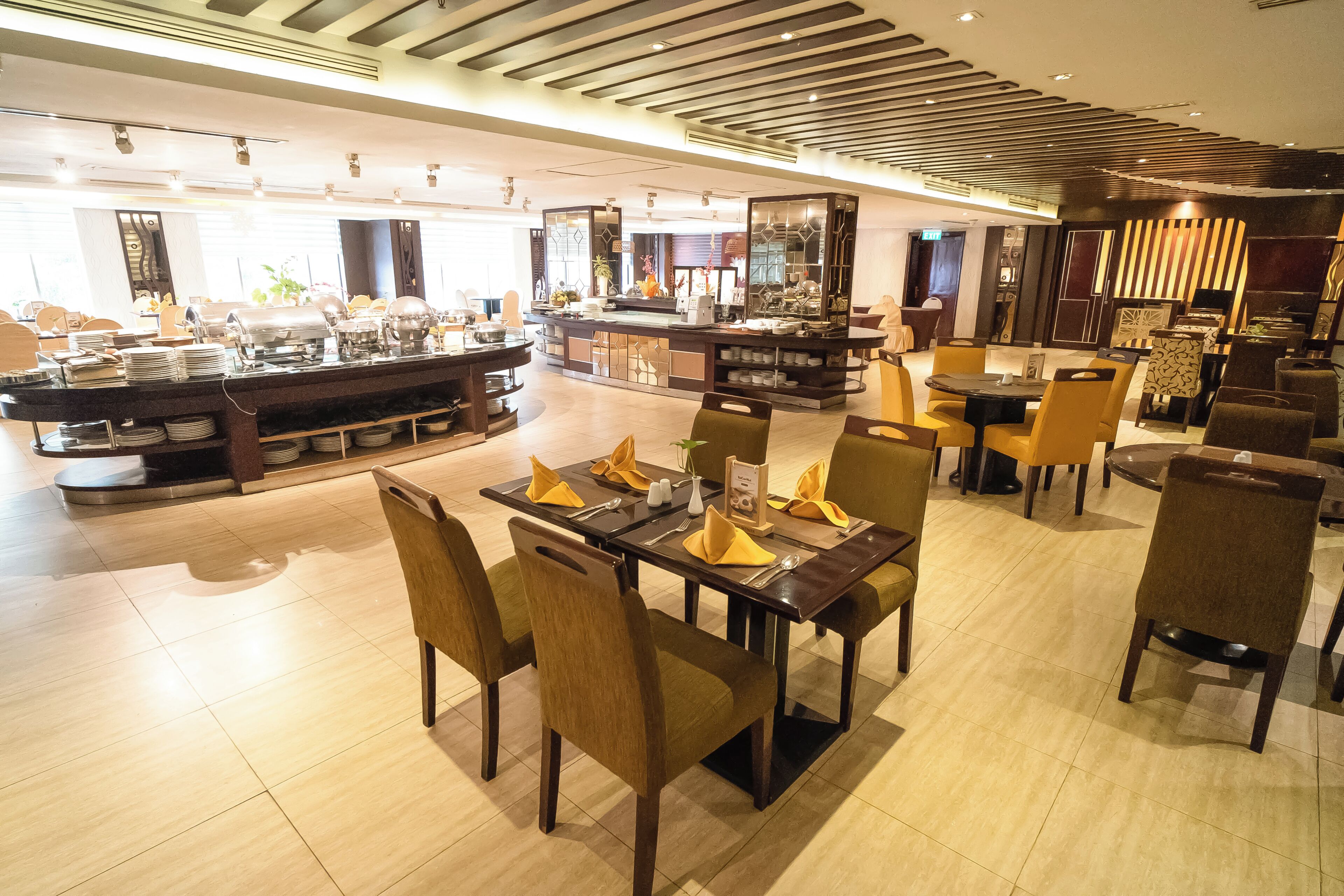 A hotel dining area with multiple tables, chairs, and a buffet station.
