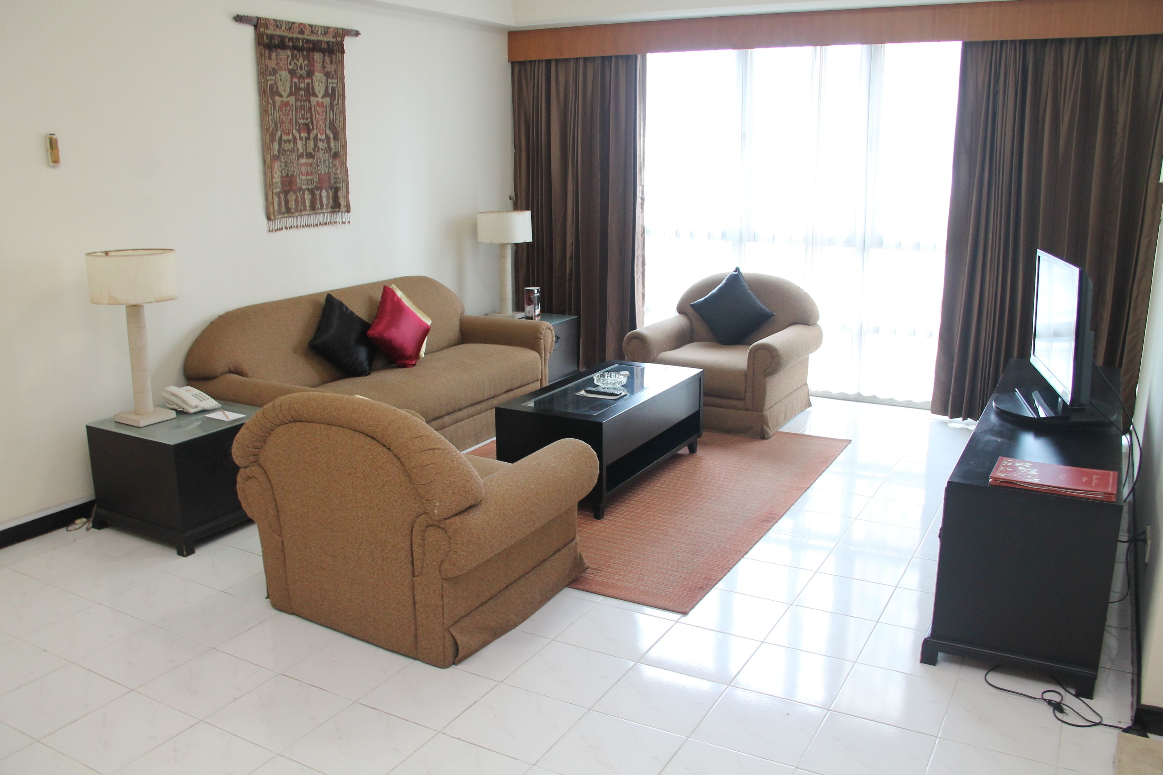 Una sala de estar con sofá, sillón, mesa de centro y mueble para televisión.