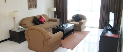 Una sala de estar con sofá, sillón, mesa de centro y mueble para televisión.