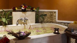Une salle de spa équipée d’une baignoire, d’une petite table avec des articles de toilette et d’une plante en pot.
