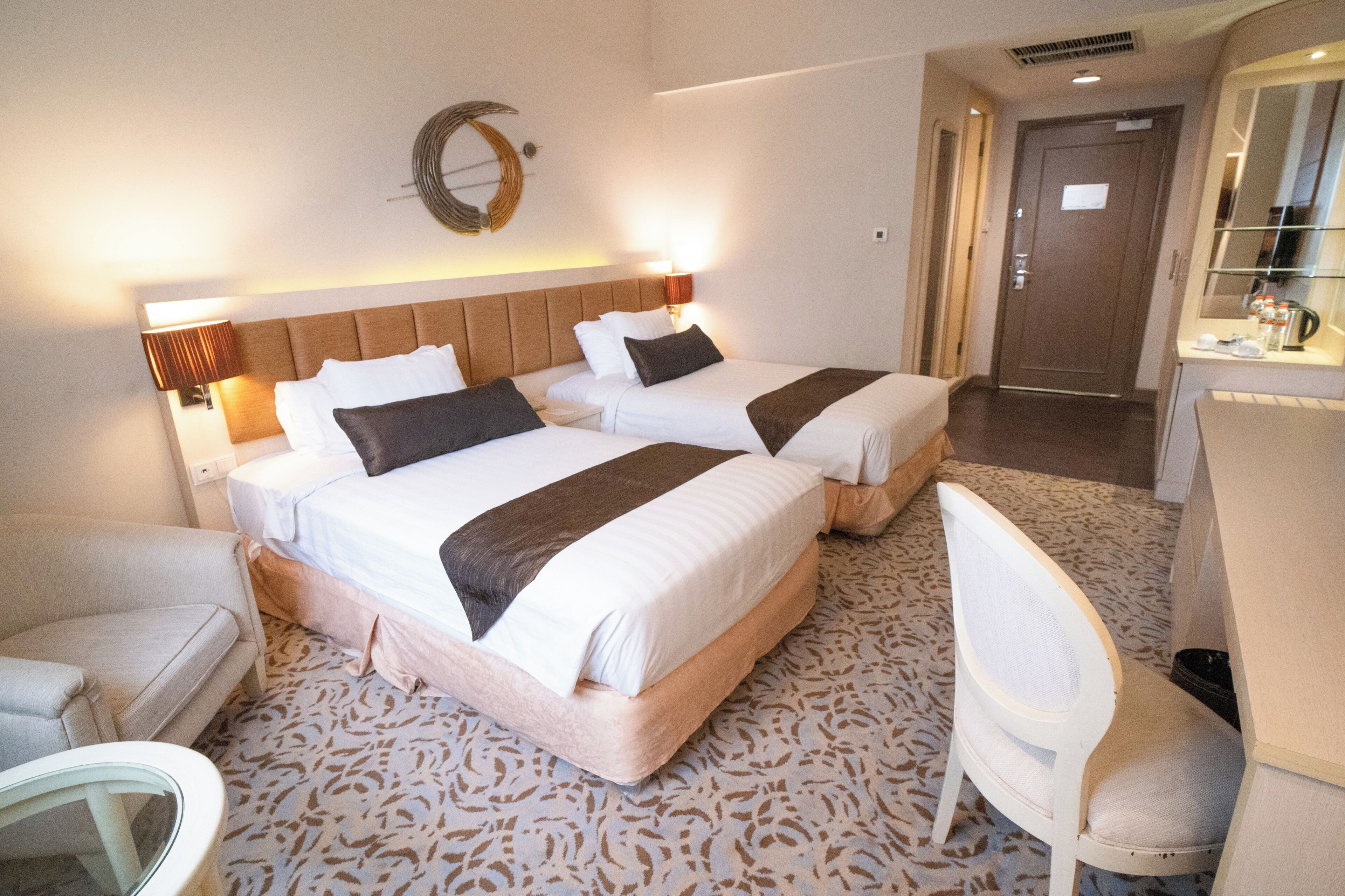 Una habitación de hotel con dos camas, una silla, un escritorio y un espejo.