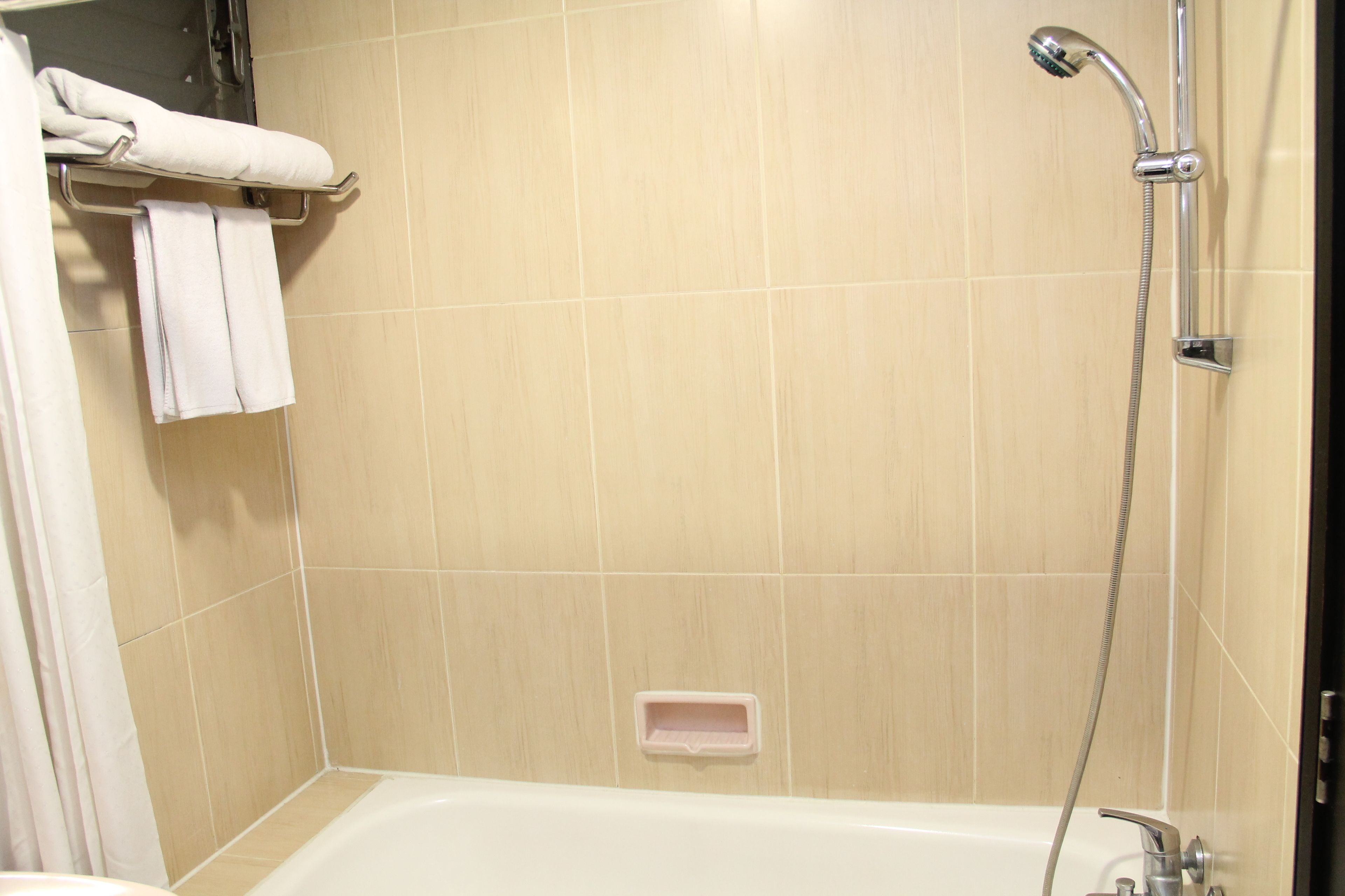 A bathroom with a bathtub, a shower, and a towel rack with towels.