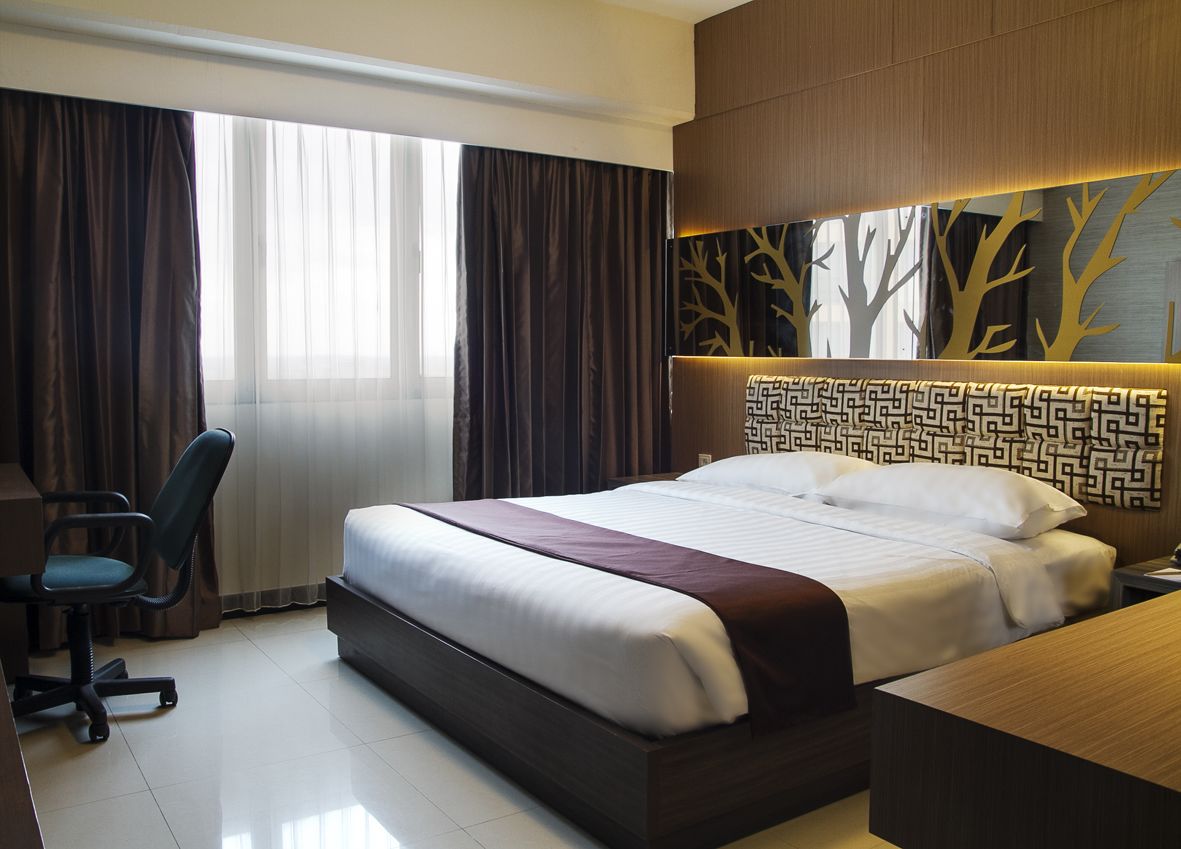A modern hotel room with a large bed, a desk, and a chair.