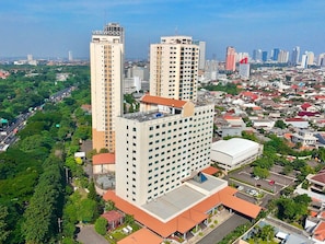 Un edificio alto con varios pisos, rodeado de una zona urbana densa y otros edificios altos.
