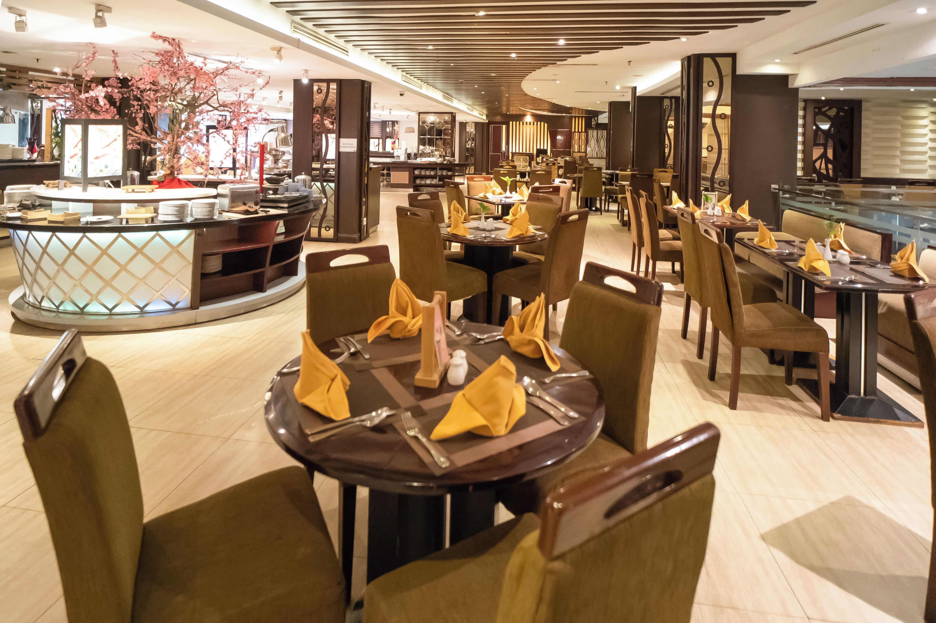 Ein Restaurant mit runden Tischen, Stühlen und einer Theke in der Mitte.