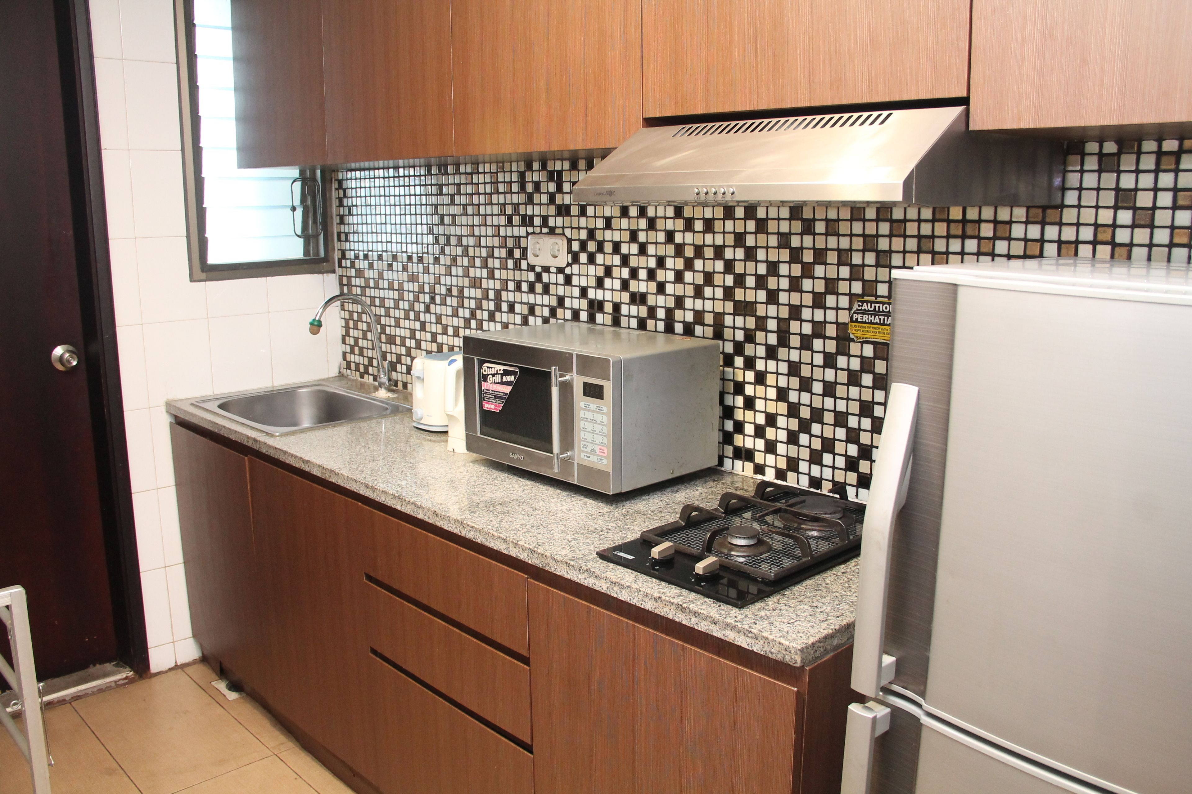 A kitchen with wooden cabinets, a microwave, a stove, and a refrigerator.