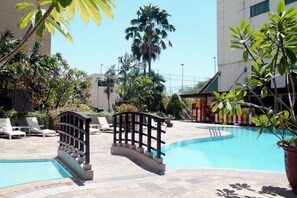 Une piscine avec un pont, des chaises longues et des plantes en pot.
