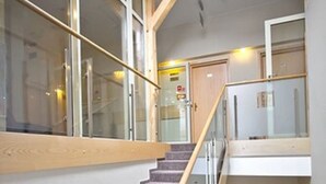 A staircase with glass railings and wooden handrails, leading to an upper level. - Kracow Residence Hotel (Krakow)
