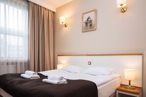 A hotel room with a bed, two bedside lamps, a painting on the wall, and a window with curtains. - Kracow Residence Hotel (Krakow)