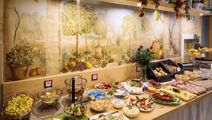 A buffet with a variety of food items and a mural of trees and fruits on the wall. - Kracow Residence Hotel (Krakow)