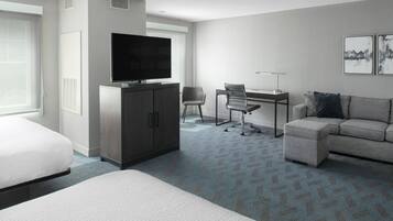 Una habitación de hotel con cama, escritorio, silla, sofá y televisor.