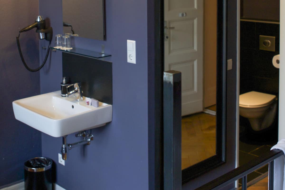 A bathroom with a white sink, a mirror, and a toilet.