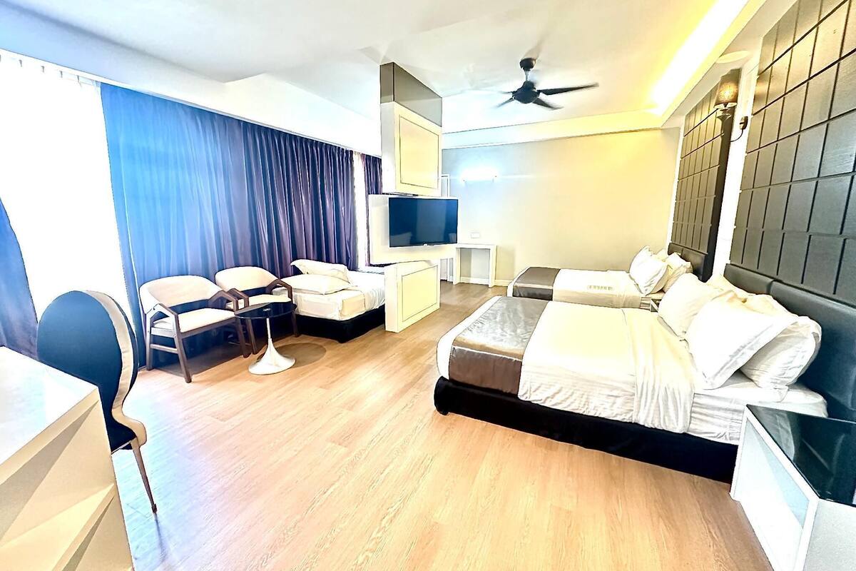 A hotel room with a bed, a desk, a chair, a TV, and a ceiling fan.