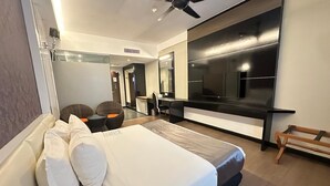 A modern hotel room with a large bed, a ceiling fan, a TV, and a seating area with a table and chairs. - The Sterling (Malacca City)