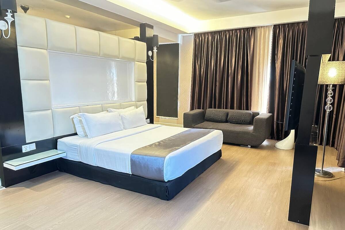 A modern hotel room with a large bed, a sofa, and a desk.