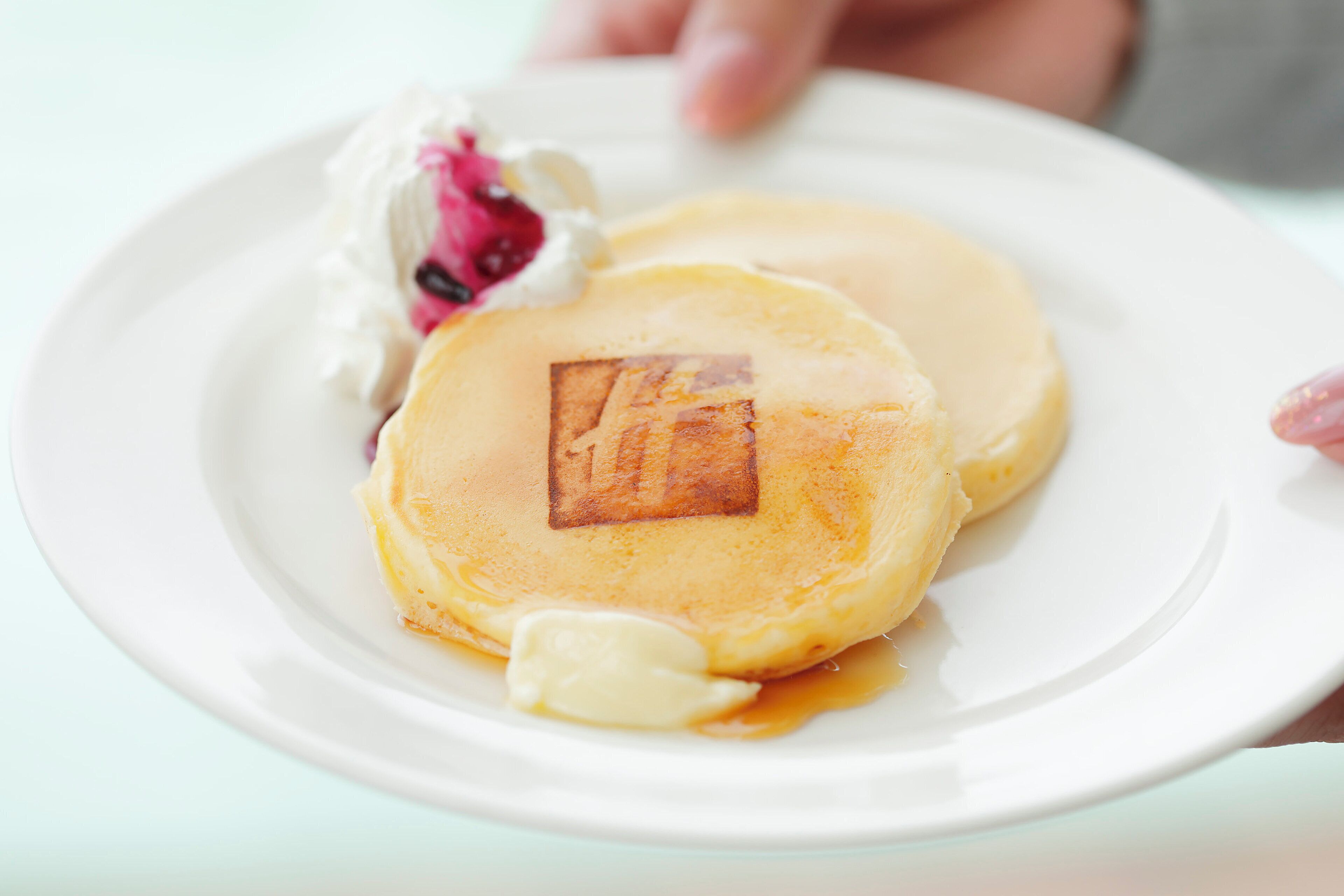 A plate with pancakes and a dollop of whipped cream.