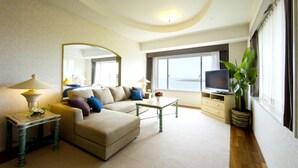 A hotel room with a sofa, a coffee table, a TV, a lamp, a mirror, and a view of the sea. - Holiday Inn ANA Miyazaki by IHG (Miyazaki)