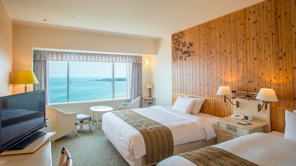 A hotel room with two beds, a TV, a small table, and a window with a view of the sea. - Holiday Inn ANA Miyazaki by IHG (Miyazaki)