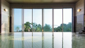 A spacious indoor swimming pool with a clear view of the ocean and palm trees through large windows. - Holiday Inn ANA Miyazaki by IHG (Miyazaki)