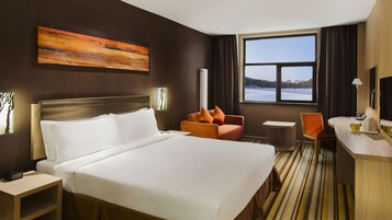 Una habitación de hotel con una cama grande, un escritorio, una silla y una ventana con vista a un paisaje nevado.