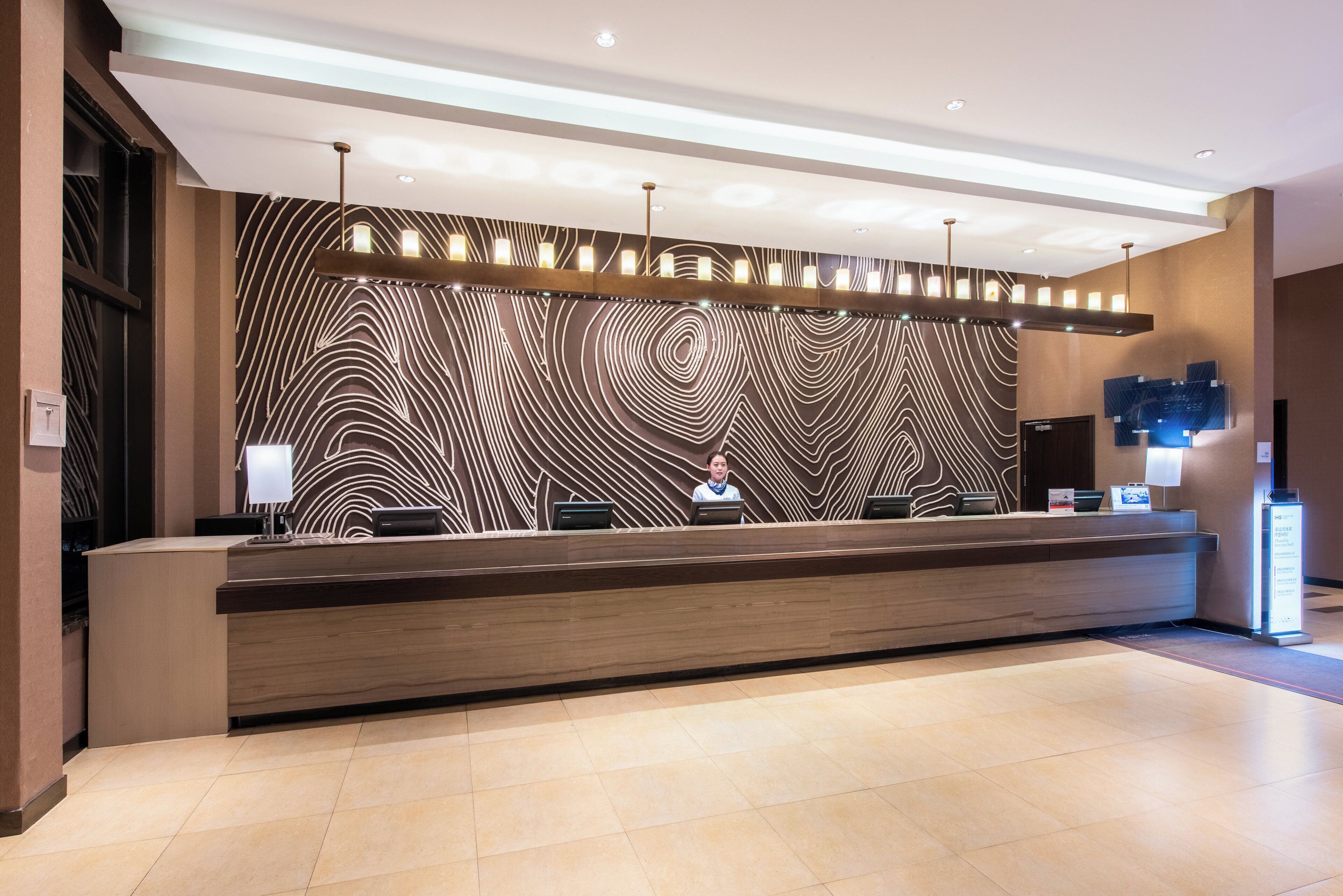 A reception desk with a modern design, a patterned wall, and a clean, tiled floor.