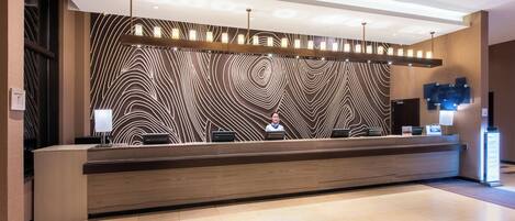 A reception desk with a modern design, a patterned wall, and a clean, tiled floor.