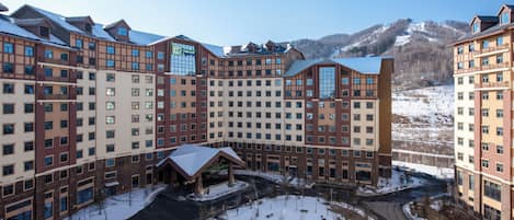 A multi-story hotel with a central courtyard, surrounded by snow-covered terrain and mountains.