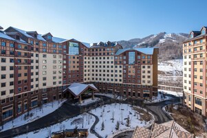 Un hotel de varios pisos con un patio central, rodeado por terreno nevado y montañas.