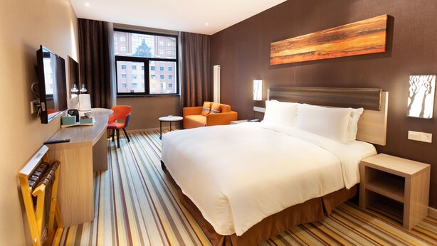A hotel room with a large bed, a desk with a chair, a small table, and a TV. - Holiday Inn Express Changbaishan by IHG (Baishan)
