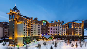 Un hotel grande con varias construcciones, un telesilla y paisajes nevados.