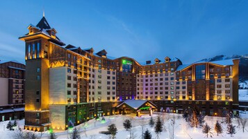 Un hotel grande con varias construcciones, un telesilla y paisajes nevados.