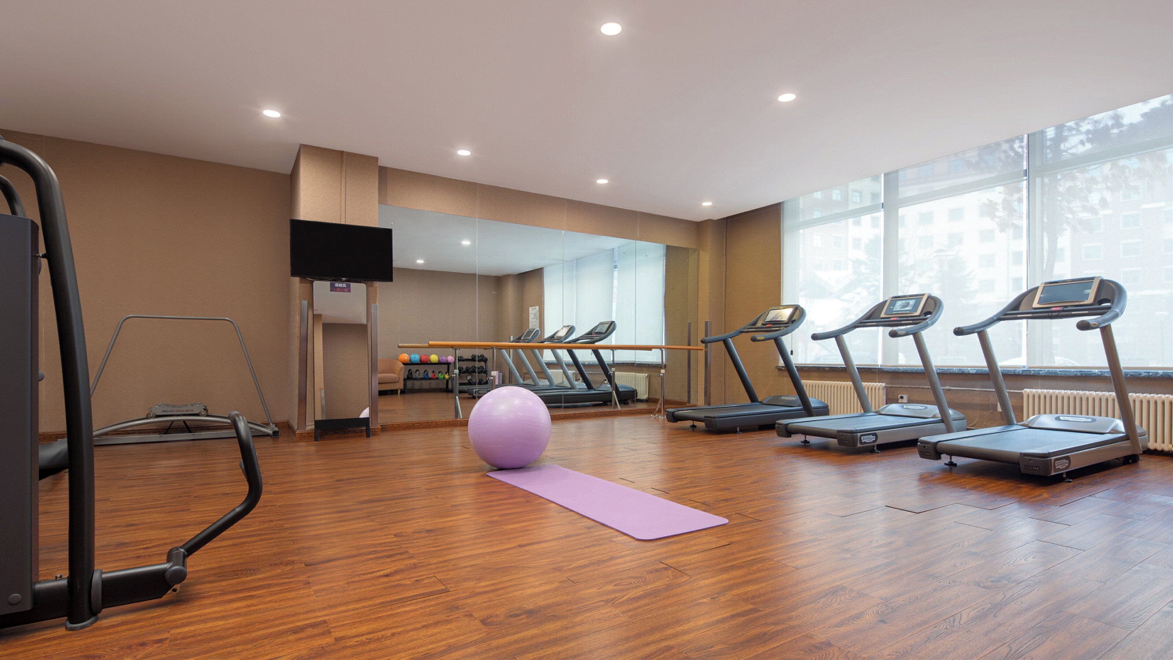 A gym with treadmills, a stationary bike, and a yoga mat.