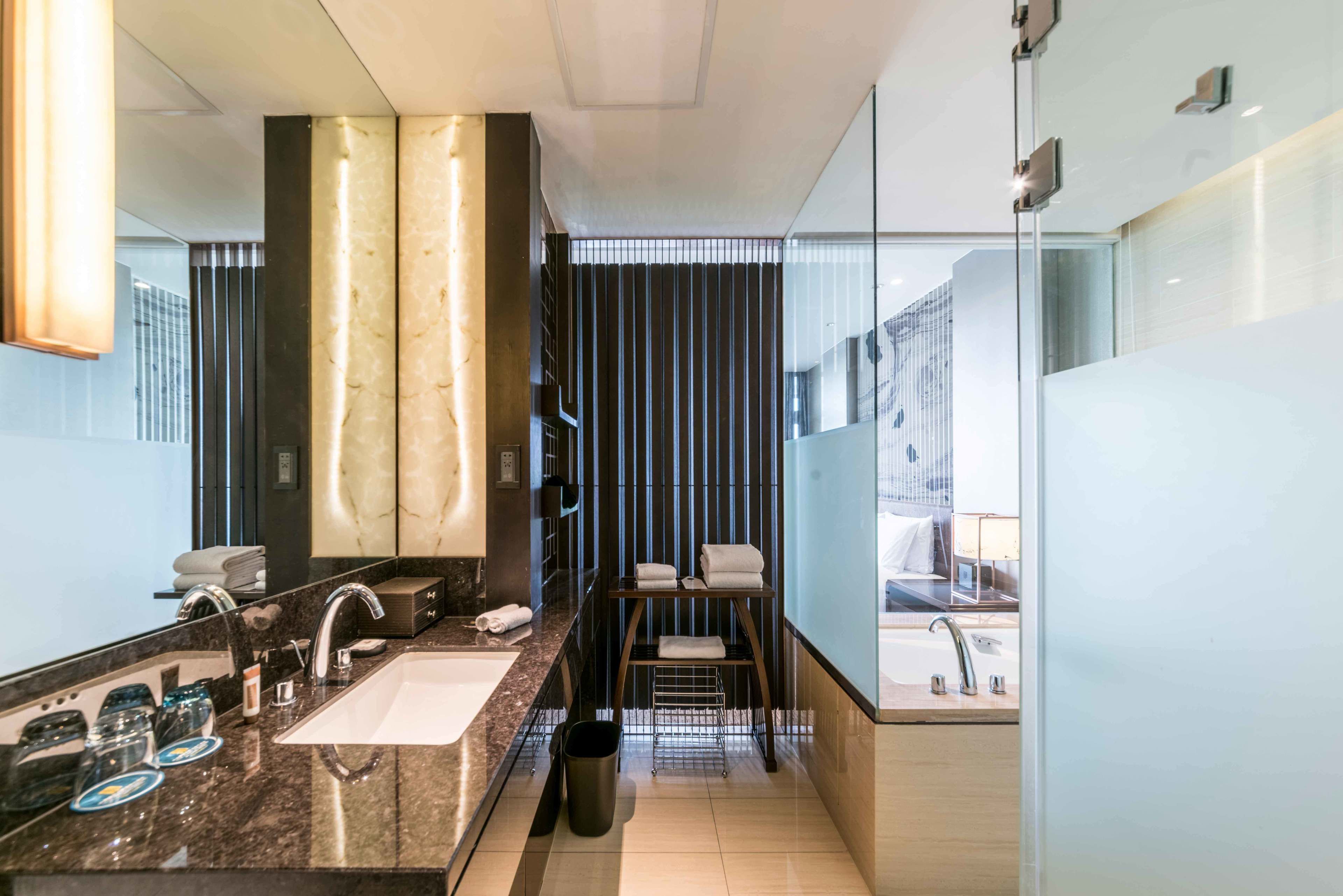A modern bathroom with a large mirror, two sinks, and a towel rack.