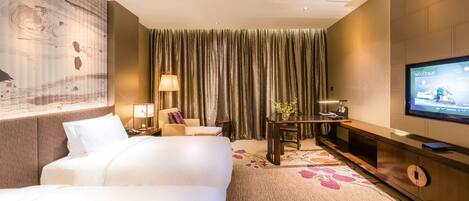 A hotel room with two beds, a television, a desk with a lamp, and a large window with curtains.