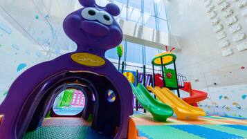 Ein Kinderspielbereich mit einem violetten Tunnel, Rutschen und einer Kletterkonstruktion.