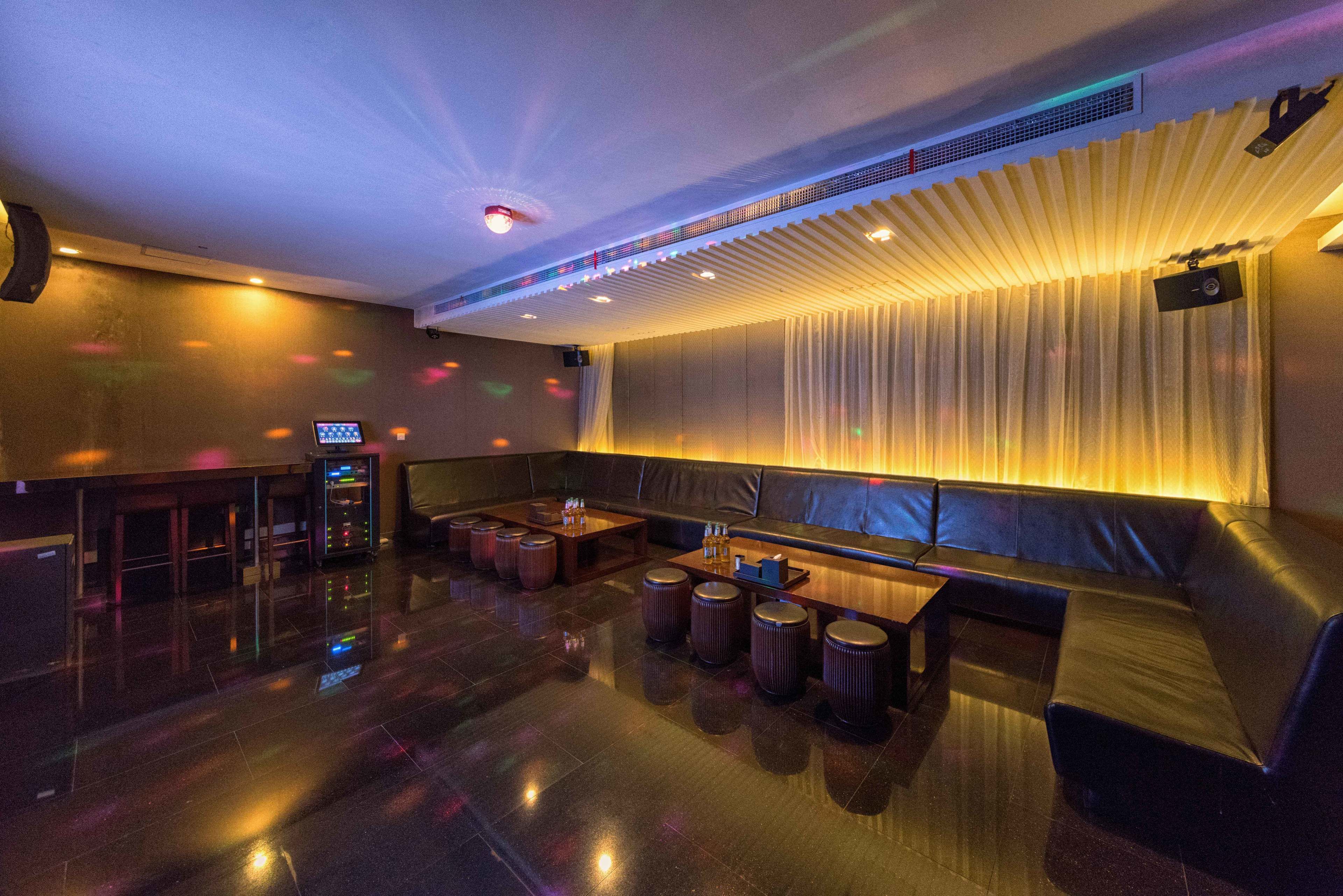 A modern lounge area with a seating arrangement, a bar, and a projection screen.