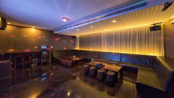 A modern lounge area with a seating arrangement, a bar, and a projection screen.