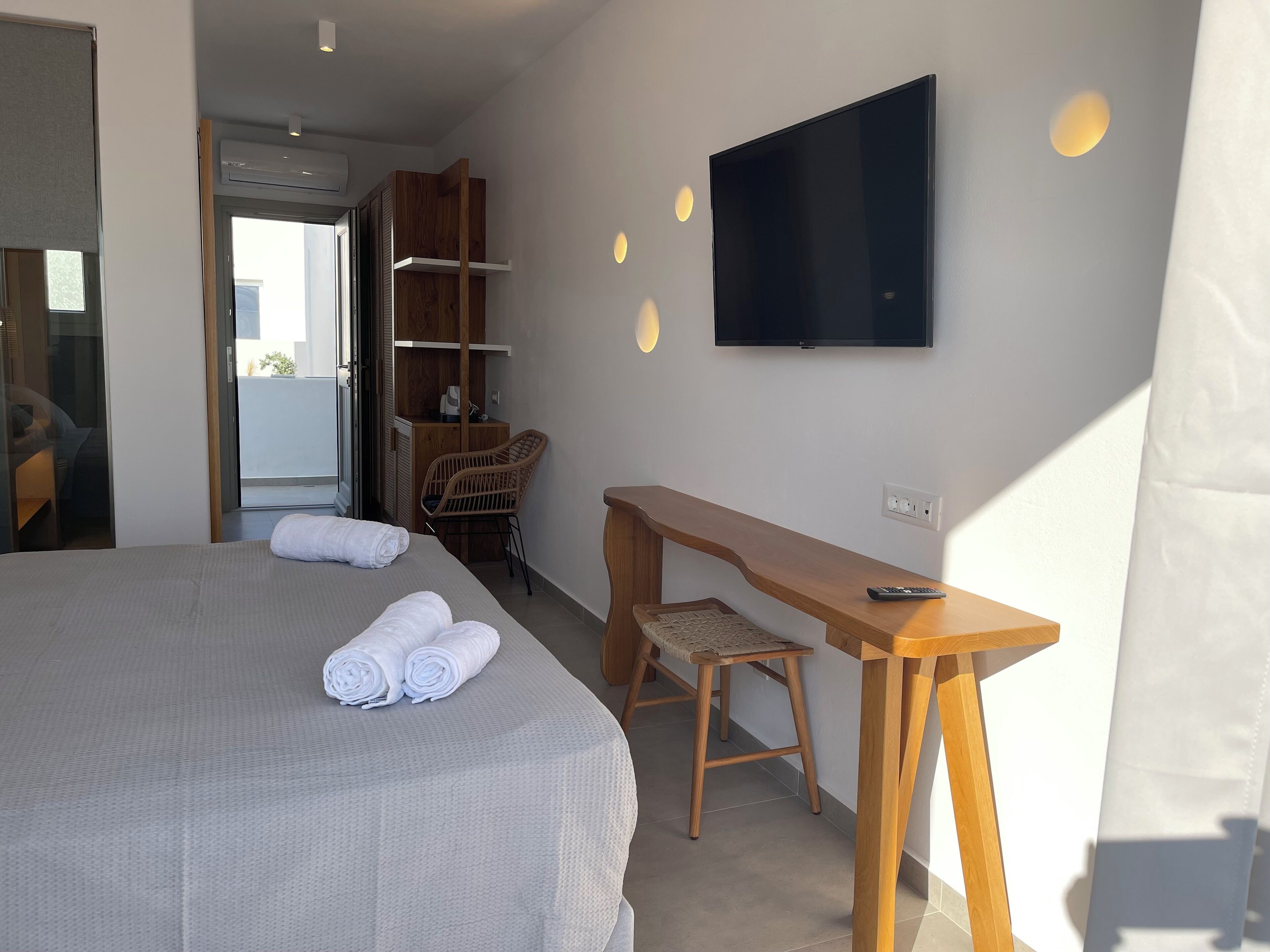 A hotel room with a bed, a desk, a chair, a TV, and a wardrobe.