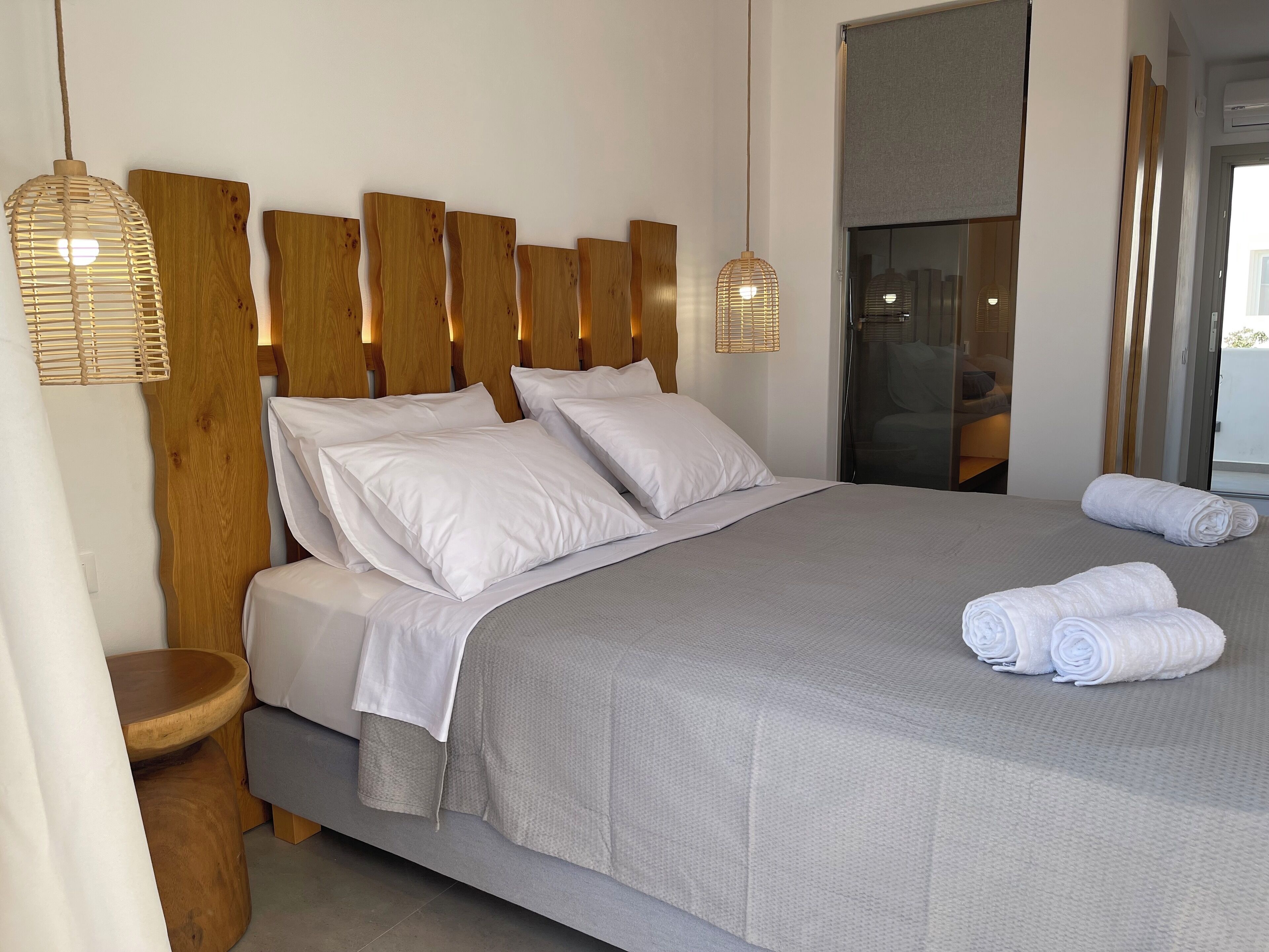 Ein modernes Hotelzimmer mit einem großen Bett, einem Holz-Kopfteil und zwei Nachttischlampen.
