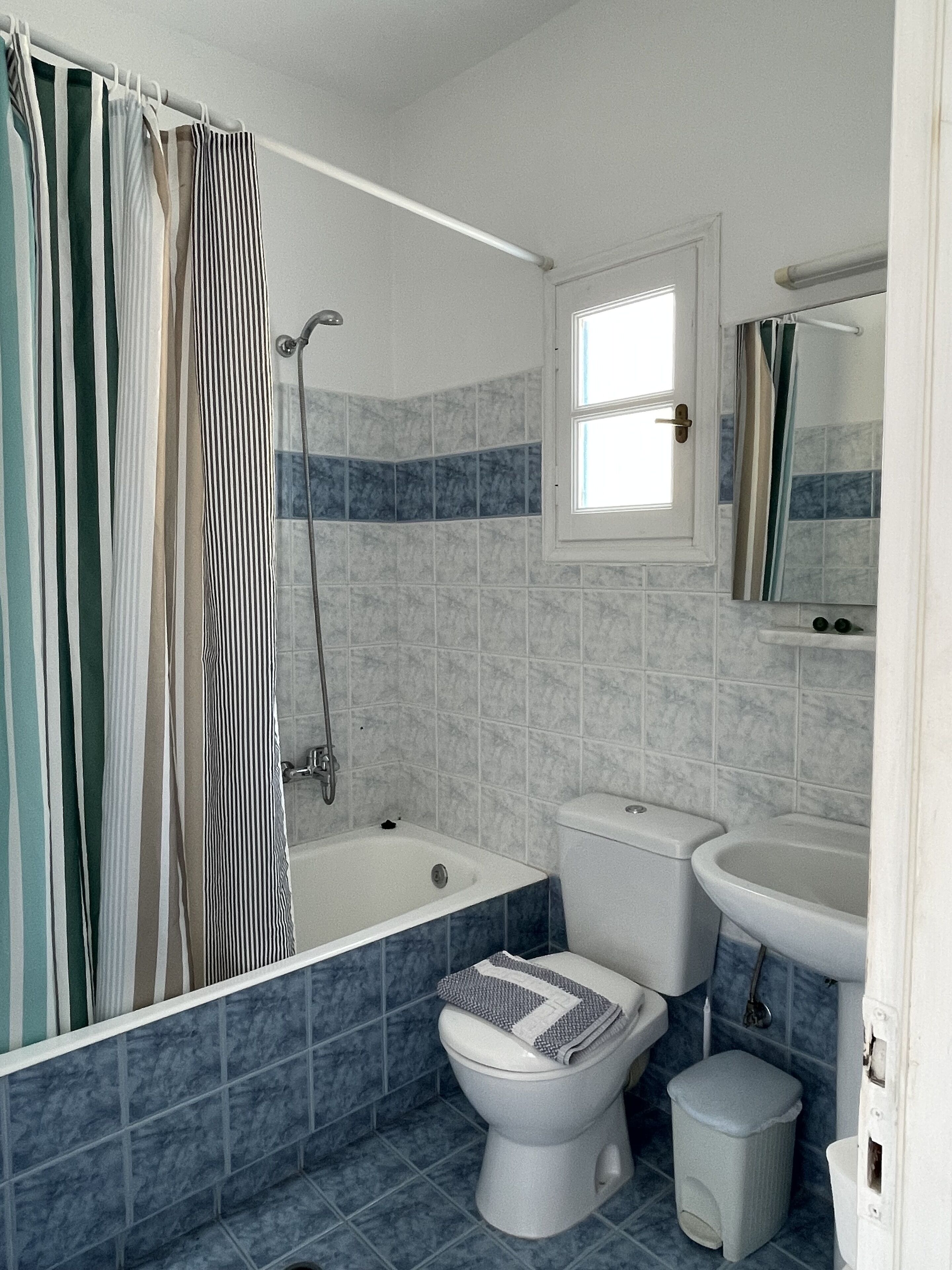 A bathroom with a bathtub, toilet, and sink, featuring blue and white tiles.
