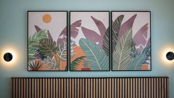 A wall-mounted triptych artwork with tropical foliage and a sun.