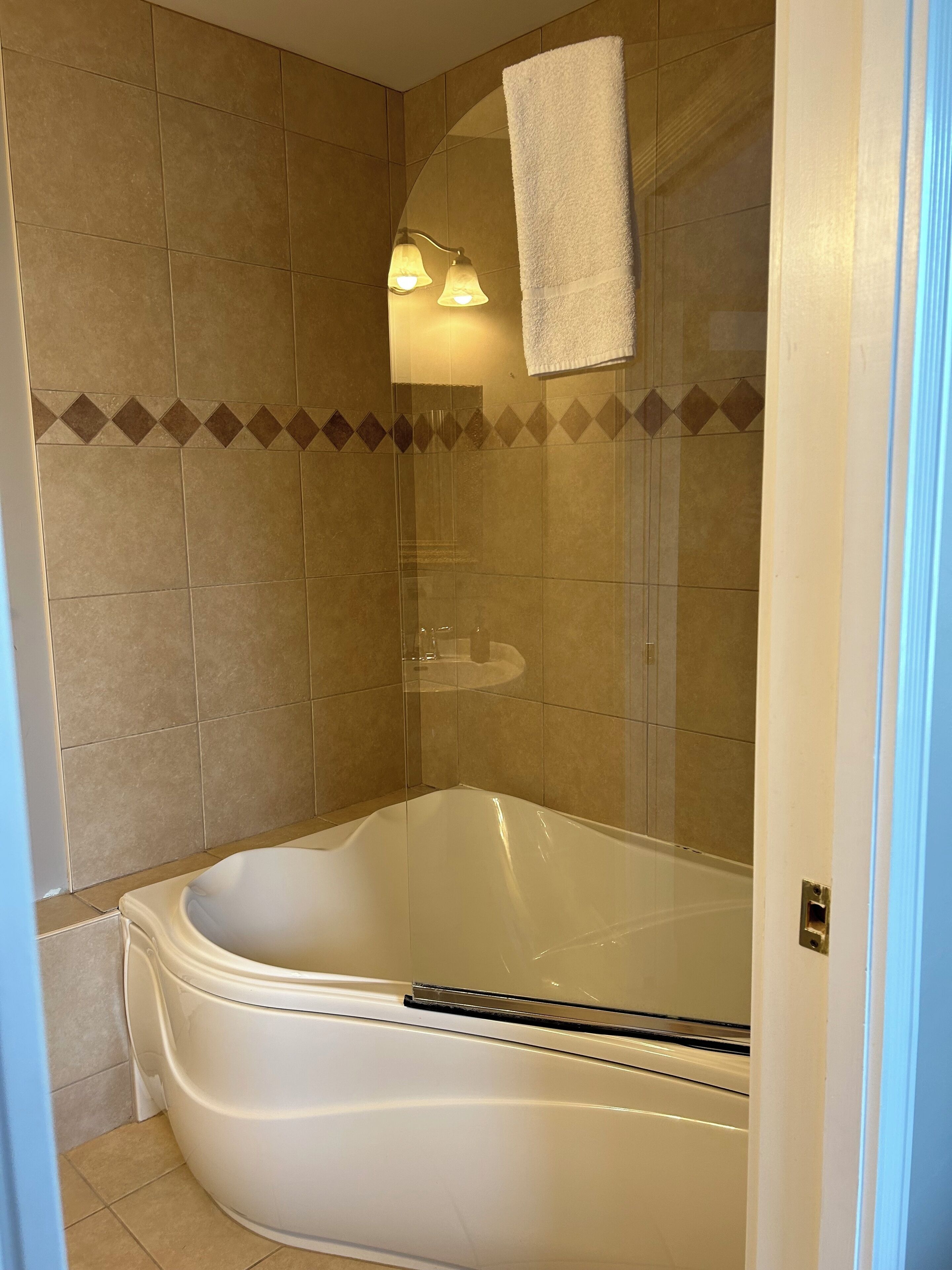 A bathroom with a bathtub, a shower, and a towel hanging on the wall.