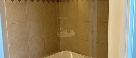 A bathroom with a bathtub, a shower, and a towel hanging on the wall.