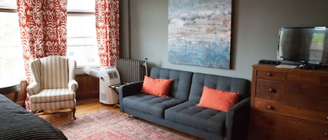 A living room with a grey sofa, striped armchair, and a red patterned rug.