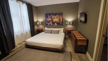 Una habitación de hotel con una cama grande, dos mesitas de noche, un televisor y un cuadro en la pared.