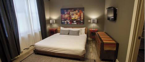 A hotel room with a large bed, two bedside tables, a TV, and a painting on the wall.