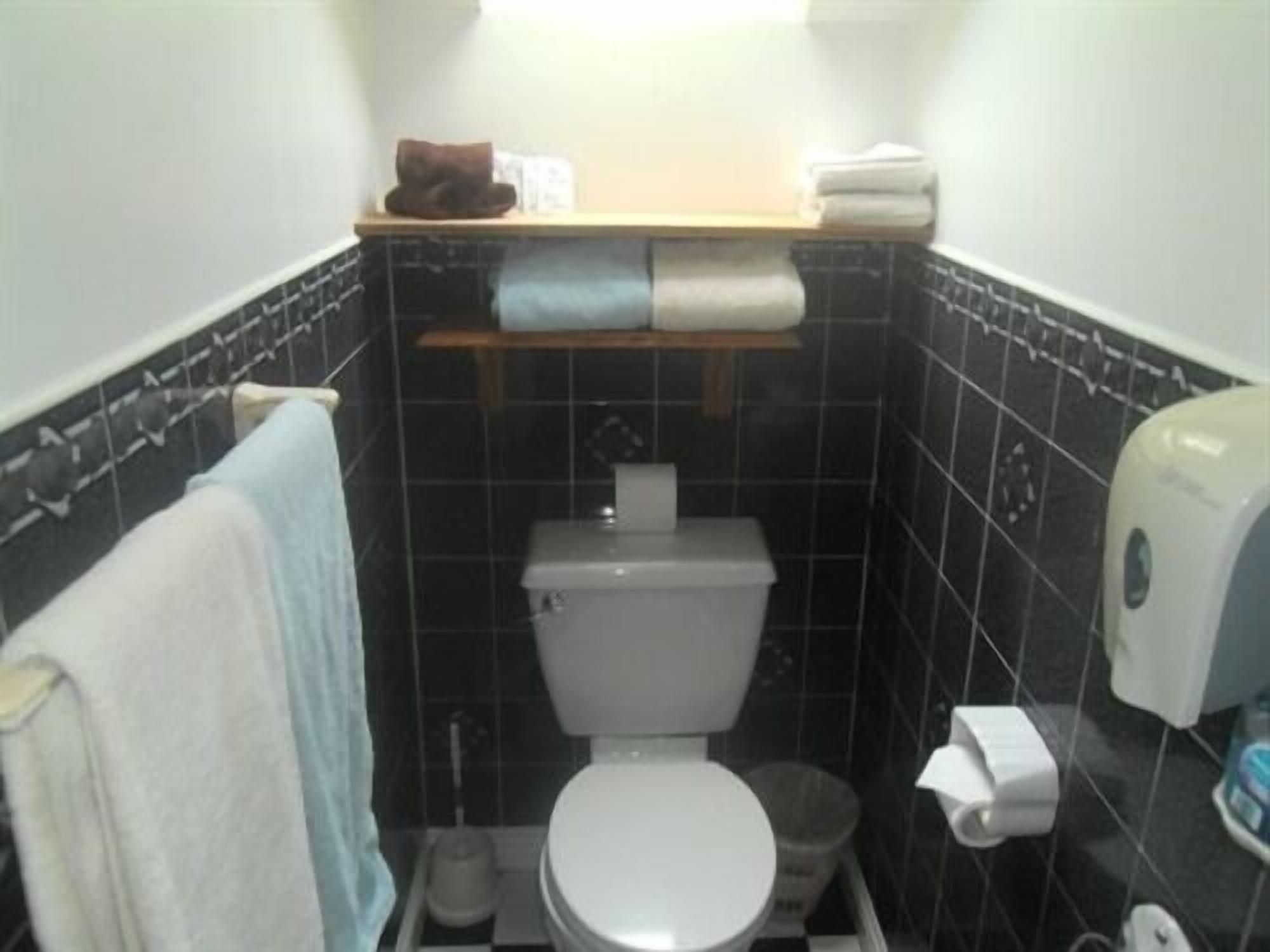 Un baño pequeño con inodoro, lavamanos y toallero.