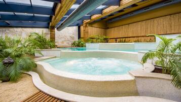 A hot tub area with a wooden deck, surrounded by plants and a stone wall.