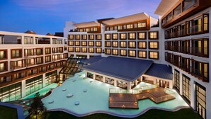 Un hotel de varios pisos con un patio central que cuenta con una piscina y zonas de estar al aire libre.