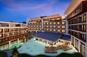 Un hotel de varios pisos con un patio central que cuenta con una piscina y zonas de estar al aire libre.